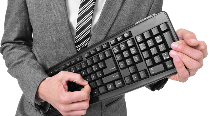 a man wearing a suit holding a computer keyboard pretending he is playing a guitar